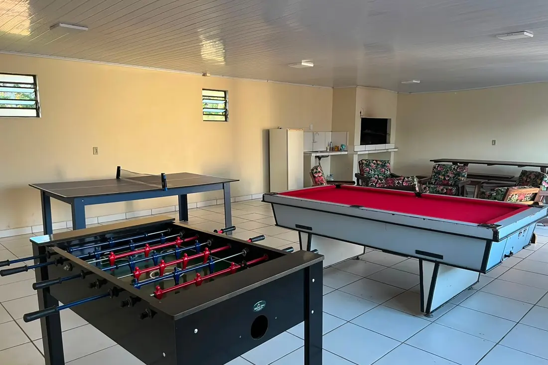 Sala de jogos com mesa de sinuca, ping-pong e pebolim